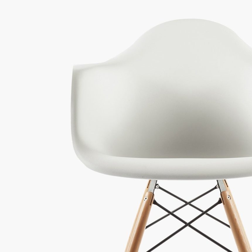Modern white chair with wooden legs against white background.